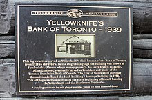 Yellowknife Heritage 2000 - Yellowknife's Bank of Toronto - 1939 - Tato struktura dřeva sloužila jako první pobočka Yellowknife Bank of Toronto v letech 1938 až 1950. V jazyce Dogrib byla budova známá jako Sombasheko („dům, kde rostou peníze“). Časný vedoucí pobočky Allan Lambert nakonec působil jako prezident a předseda kanadské banky Toronto Dominion Bank. Výbor pro dědictví města Yellowknife prohlásil budovu banky za budovu dědictví v roce 1998. Tato stará struktura protokolu představuje počátek počátků bankovnictví poboček v Yellowknife a na severozápadních územích. * Pomoc s financováním této desky poskytovaná finanční skupinou TD Bank