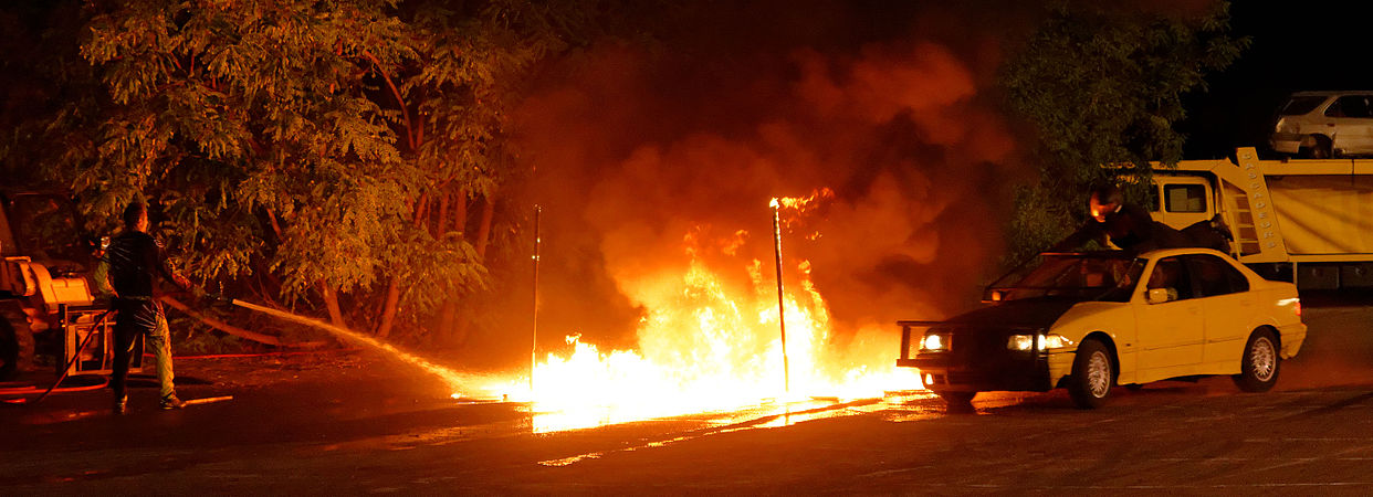 Passage dans le feu, d'une voiture à laquelle s'accroche un cascadeur (sur le toit).