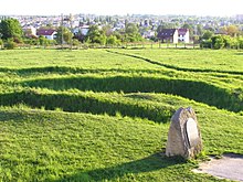 Gedenkplaat en loopgraven bedekt met gras