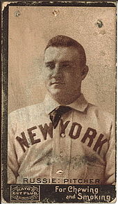 A baseball player is seen from his chest up, facing slightly left of the camera.
