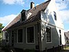 Houten huis met aan de straat een puntgevel met fronton