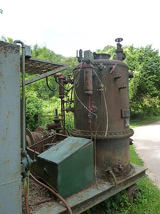 Derelict boiler at Clearwell Caves.
Note the bolted joint to allow the boiler shell to be dismantled for cleaning. The green box encloses the electric fan for an oil spray burner. The two vertical cylinders are Mobrey automatic water-level valves controlling the feedwater level. Clarkson thumble tube boiler, burner side, Clearwell Caves.jpg
