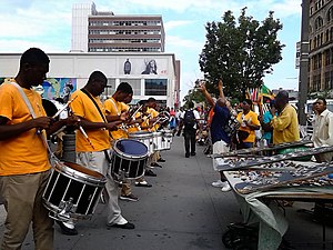 Band rehearsal on 125th Street in Harlem, the historic epicenter of African American culture. New York City is home by a significant margin to the world's largest Black population of any city outside Africa, at over 2.2 million. African immigration to New York City has contributed the majority of the Black population growth since 2000. Harlem Street rehearsal (125th street).jpg