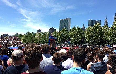 Clinton delivers the speech at her kickoff rally. The United Nations, Empire State Building, and Chrysler Building can be seen in the background.