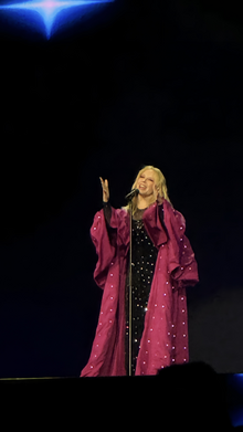 A Caucasian woman wearing a black and pink outfit while performing on stage