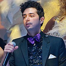 A man wearing a tuxedo singing into a microphone