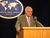 Michael Novak behind a lecturn, speaking at the Foreign Press Center in Washington.