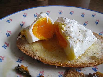 A runny poached egg on bread, cut in half