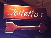 Bathroom sign in French restaurant in USA, spelling "Toilets" to convey a French aura, but understood by unilingual English speakers.