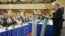 Putin delivers the Munich speech with the United States delegation led by Senator John McCain and Joe Lieberman and Secretary of Defense Robert Gates watching on in the background. Putin in Munchen.jpg