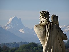 Ön planda bir heykel ile karla kaplı bir dağın görünümü.