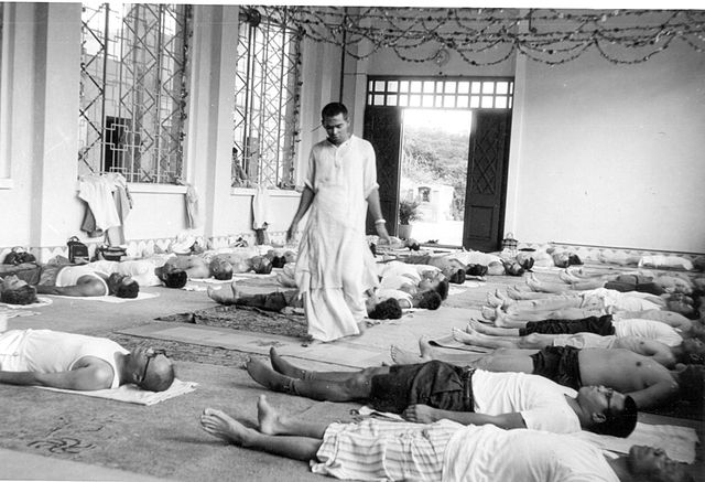 Vishnudevananda with a Sivananda yoga class relaxing in Shavasana