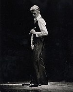 David Bowie wears a white shirt and black trousers singing in 1976 in character as the Thin White Duke