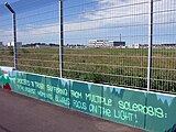 Graffito von Tom Brane: City of Freiburg am Freiburger Flugplatz, im Hintergrund das Fraunhofer-Institut für Physikalische Messtechnik IPM