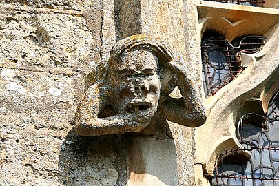 Gargoyle with toothache on a medieval Anglican church (All Saints' Church, Holton cum Beckering, England).
