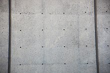 Facade of the J. Edgar Hoover Building, showing holes where cladding was to have been attached to the raw concrete Unused cladding holes - east facade - J Edgar Hoover Building - Washington DC - 2012.jpg