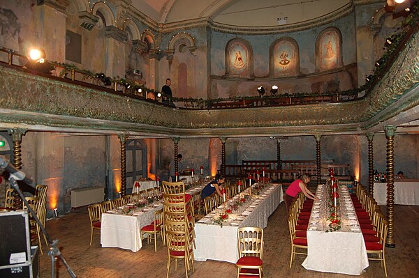 The interior of Wilton's Music Hall (here, being set for a wedding). The line of tables give some idea of how early music halls were used as supper cl