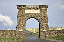 Un gran arco de piedra natural de forma irregular sobre una carretera