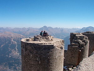 Ruined artillery batteries with people sitting on top of turret #4 of a total of 8