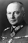 Black-and-white portrait of an older man wearing a military uniform with an Iron Cross displayed at his neck, his hair is combed back.