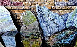 Una imagen de unas losas de mármol de Connemara contra una pared.  Cada losa tiene remolinos de colores, el del medio se destaca porque toda la losa es de color verde musgo.