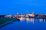 Mehrere barocke Gebäude in der Dresdner Altstadt spiegeln sich in der Elbe.