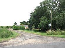 Bir madenci yoldan çıkan küçük çiftlik yolu. alçak bir çitin arkasında bazı tek katlı tuğla çiftlik binaları dikizliyor. Resmin sağ tarafında kocaman bir ağaç var