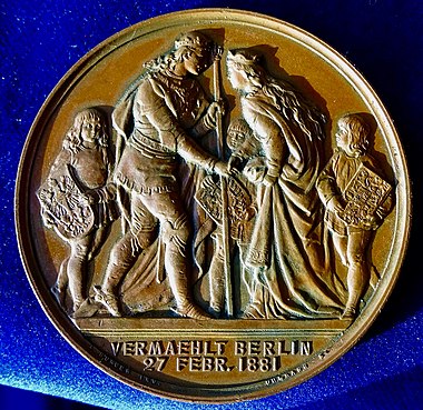 The reverse shows the couple in Medieval costumes in front of 3 squires carrying the shields of Prussia, Germany, and Schleswig-Holstein.