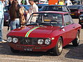 Ein Lancia Fulvia Coupé HF (1965), mit dem historischen roten Montebello, aktualisiert durch ein gelb-blaues Turiner Band