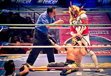 Liger tearing at Último Guerrero's mask during a CMLL match