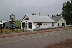 Bangunan tua dengan tanda selamat datang dan papan buletin komunitas di Petapa, Wyoming.jpg