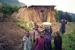Photograph depicting seven rural children, with a straw house and farmland in the background, taken in the Volcanoes National Park in 2005