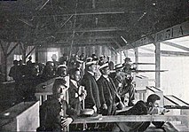 Photo d'un stand de tir couvert avec des hommes pointant des carabines en direction du champ de tir.