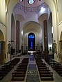 Transetto della chiesa con al fondo la statua del Murialdo sormontata dalla vetrata policroma.