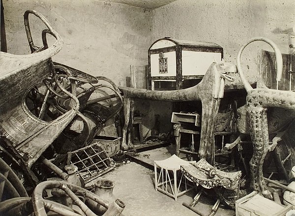 View of the southwest corner of the antechamber, with disassembled chariots on the left and furniture on the right. The entrance to the annexe is bene