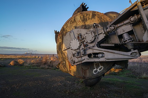 Rusted bucket wheel excavator in front of former lignite-fired power plant