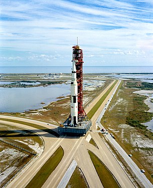 La Saturn V sur sa plateforme de lancement en route pour le pas de tir apparaissant en arrière plan au loin (Apollo 14, 1970).