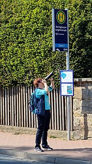 Миниатюра для Файл:Barsinghausen Bergamtstraße Bärbel Miemietz mit Teleobjektiv an der Bushaltestelle Langenkampstraße.jpg