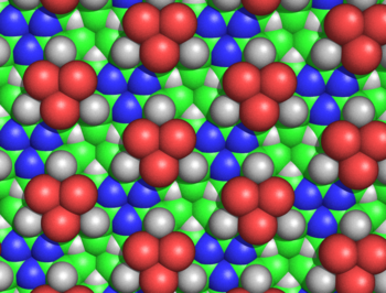 Figure 5: Spacefilling diagram of the alanine cyclol fabric, as seen from the side where none of the C atoms emerge. This Figure shows the threefold symmetry of the fabric and also its extraordinary density; for example, in the "lacunae"--where three C atoms (shown in green) and three H atoms (shown as white triangles) converge--the carbons and hydrogens are separated by only 1.68 A. The larger green spheres represent the C atoms; the C atoms are generally not visible, except as little triangles next to the blue nitrogen atoms. As before, the red atoms represent hydroxyl groups, not carbonyl oxygen atoms. Cyclol fabric spacefilling OHside.png