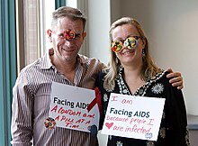 People wearing AIDS awareness signs. On the left: "Facing AIDS a condom and a pill at a time"; on the right: "I am Facing AIDS because people I  are infected" FACING AIDS a condom and a pill at a time - I am FACING AIDS because people I -3 are infected. (5202985364).jpg