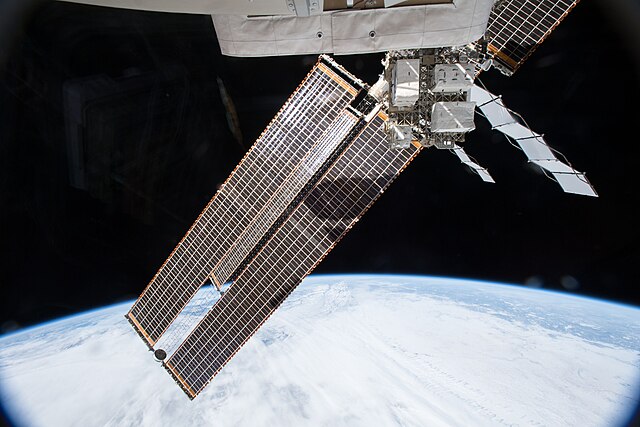 The International Space Station's black solar panels on the left and white radiators on the right