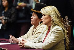 Martha Yujra seated next to Jeaning Áñez in the Palacio Quemado