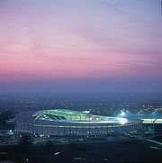 A view at twilight looking down onto a modern brightly lighted circular football stadium