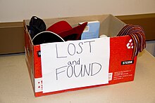 A "lost and found" box containing a book, a scarf, a hat and other items Lost and Found Box (6947296049).jpg