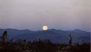 Aram-temaram pagi di gunung dengan bulan terbenam.