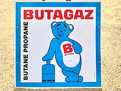 Plaque émaillée publicitaire Butagaz avec l’emblématique Bob, l’ours bleu.