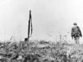 His bayoneted rifle marking the spot for burial detail, the poncho covered form of a Marine lies on a Saipan battlefield