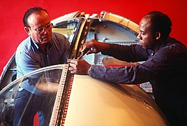 Two workers install a section of canopy on an F-111 aircraft cockpit used for conducting tests at the Bird Impact Range. A cannon at the range can fire a four-pound chicken at speed - DPLA - 1ea21a568180a6079ea3d1048b2cbbae.jpeg