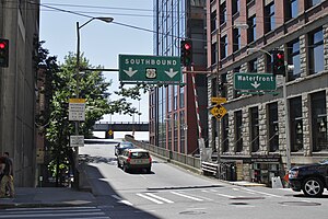 A set of green highway signs reading "Southbound US 99" and "Waterfront" seen above a street intersection.