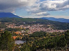 photo : une ville entourée de verdure et de montagnes.